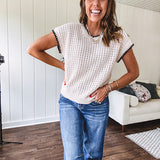 Light khaki crochet knit sweater with short sleeves and contrasting black trim at the round neck and cuffs with a wide ribbed hem.