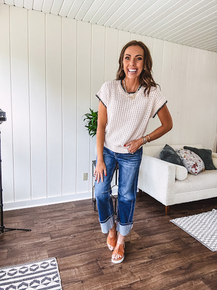 Light khaki crochet knit sweater with short sleeves and contrasting black trim at the round neck and cuffs with a wide ribbed hem.