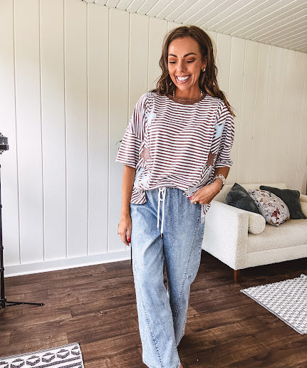 Oversized terry knit short sleeved top with cream, espresso and light blue striping and star patches throughout with exposed seams down the sides of the front and a split front hem.