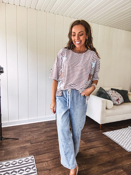 Oversized terry knit short sleeved top with cream, espresso and light blue striping and star patches throughout with exposed seams down the sides of the front and a split front hem.