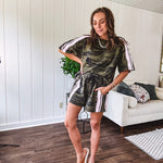 Thin, lightweight dark camo shorts with elastic drawstring waist, side pockets and light pink striping and lace detail down the sides.