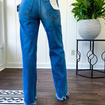 Medium wash ultra high rise straight leg jeans with no distressing throughout, but distressed hem.