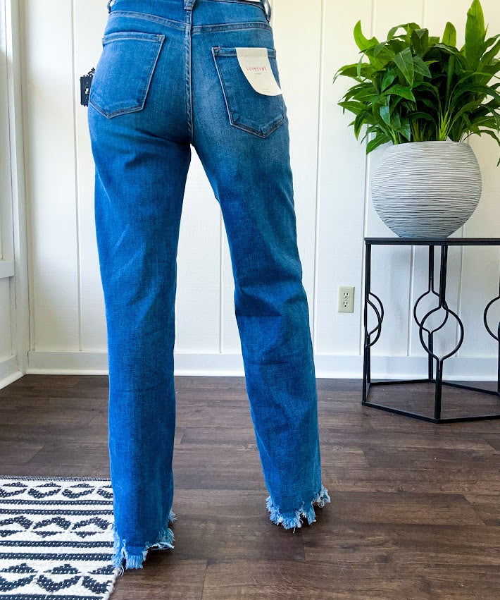 Medium wash ultra high rise straight leg jeans with no distressing throughout, but distressed hem.