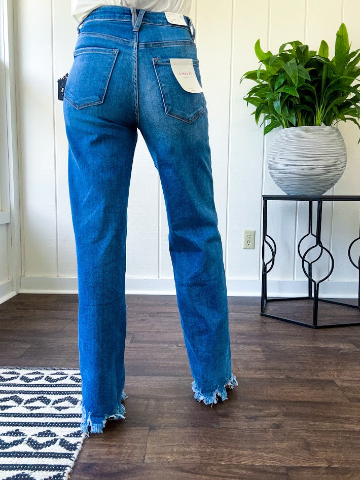 Medium wash ultra high rise straight leg jeans with no distressing throughout, but distressed hem.