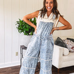 Vintage light wash denim and twill overalls with silver metal adjustable strap hardware, side zip, side and back pockets with ivory eyelet trim and cutouts throughout, wide leg design.