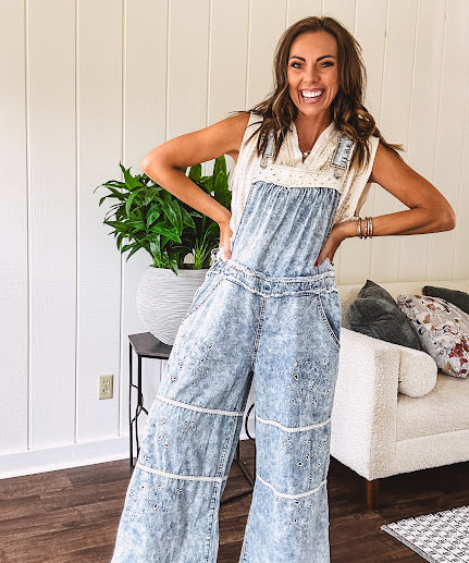 Vintage light wash denim and twill overalls with silver metal adjustable strap hardware, side zip, side and back pockets with ivory eyelet trim and cutouts throughout, wide leg design.