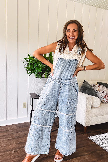 Vintage light wash denim and twill overalls with silver metal adjustable strap hardware, side zip, side and back pockets with ivory eyelet trim and cutouts throughout, wide leg design.