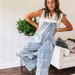 Vintage light wash denim and twill overalls with silver metal adjustable strap hardware, side zip, side and back pockets with ivory eyelet trim and cutouts throughout, wide leg design.