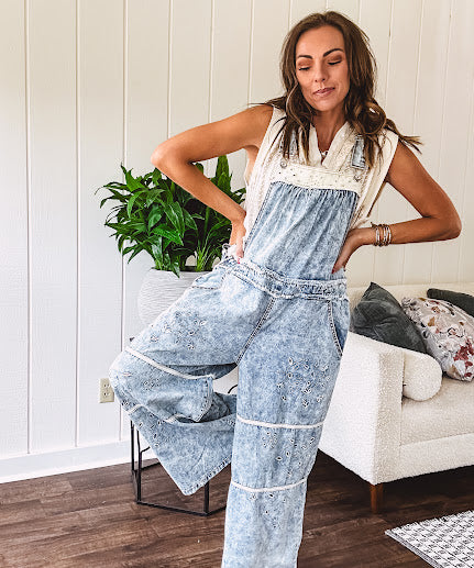 Vintage light wash denim and twill overalls with silver metal adjustable strap hardware, side zip, side and back pockets with ivory eyelet trim and cutouts throughout, wide leg design.