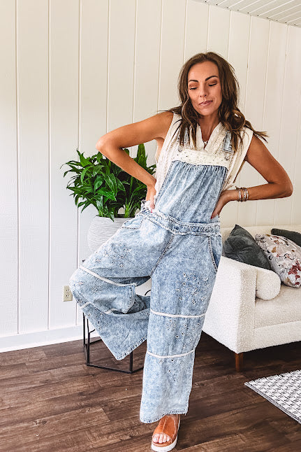 Vintage light wash denim and twill overalls with silver metal adjustable strap hardware, side zip, side and back pockets with ivory eyelet trim and cutouts throughout, wide leg design.