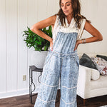 Vintage light wash denim and twill overalls with silver metal adjustable strap hardware, side zip, side and back pockets with ivory eyelet trim and cutouts throughout, wide leg design.