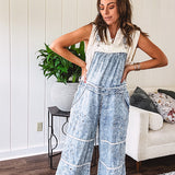 Vintage light wash denim and twill overalls with silver metal adjustable strap hardware, side zip, side and back pockets with ivory eyelet trim and cutouts throughout, wide leg design.