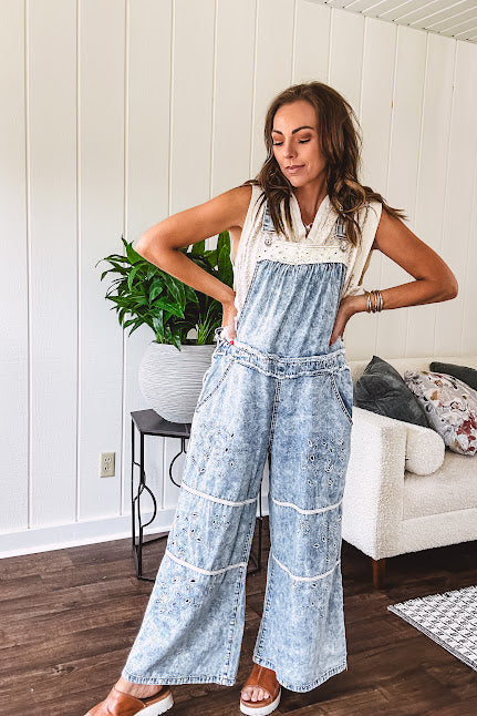Vintage light wash denim and twill overalls with silver metal adjustable strap hardware, side zip, side and back pockets with ivory eyelet trim and cutouts throughout, wide leg design.