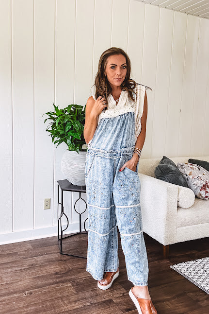 Vintage light wash denim and twill overalls with silver metal adjustable strap hardware, side zip, side and back pockets with ivory eyelet trim and cutouts throughout, wide leg design.