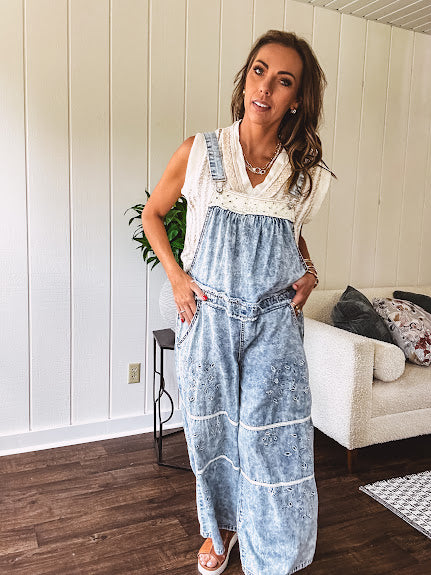 Vintage light wash denim and twill overalls with silver metal adjustable strap hardware, side zip, side and back pockets with ivory eyelet trim and cutouts throughout, wide leg design.