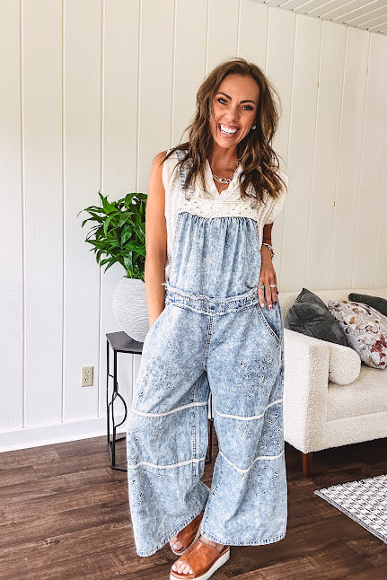 Vintage light wash denim and twill overalls with silver metal adjustable strap hardware, side zip, side and back pockets with ivory eyelet trim and cutouts throughout, wide leg design.