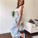 Vintage light wash denim and twill overalls with silver metal adjustable strap hardware, side zip, side and back pockets with ivory eyelet trim and cutouts throughout, wide leg design.
