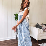 Vintage light wash denim and twill overalls with silver metal adjustable strap hardware, side zip, side and back pockets with ivory eyelet trim and cutouts throughout, wide leg design.