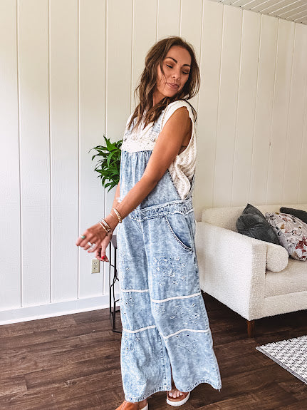 Vintage light wash denim and twill overalls with silver metal adjustable strap hardware, side zip, side and back pockets with ivory eyelet trim and cutouts throughout, wide leg design.