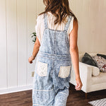 Vintage light wash denim and twill overalls with silver metal adjustable strap hardware, side zip, side and back pockets with ivory eyelet trim and cutouts throughout, wide leg design.
