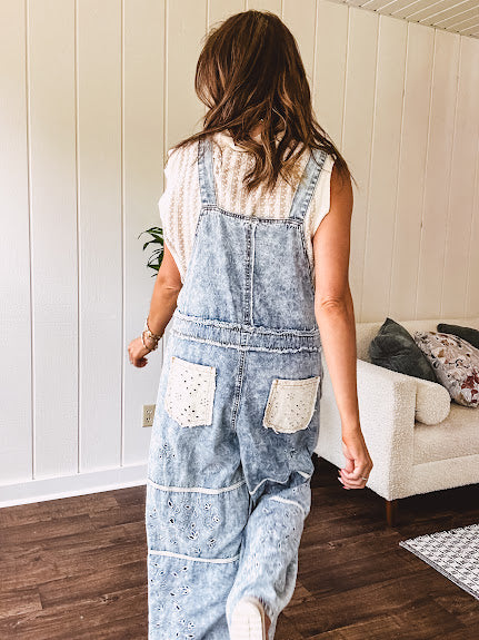 Vintage light wash denim and twill overalls with silver metal adjustable strap hardware, side zip, side and back pockets with ivory eyelet trim and cutouts throughout, wide leg design.