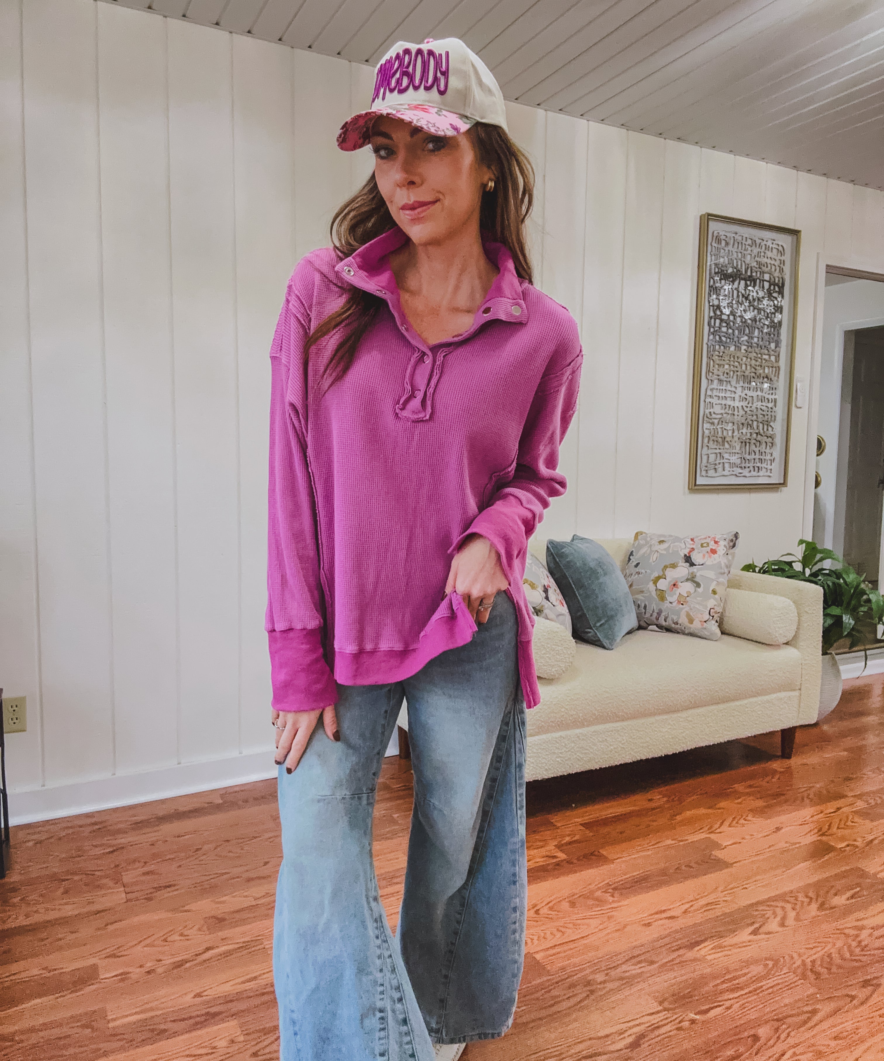 Woman wearing a pink long-sleeve top and jeans indoors.