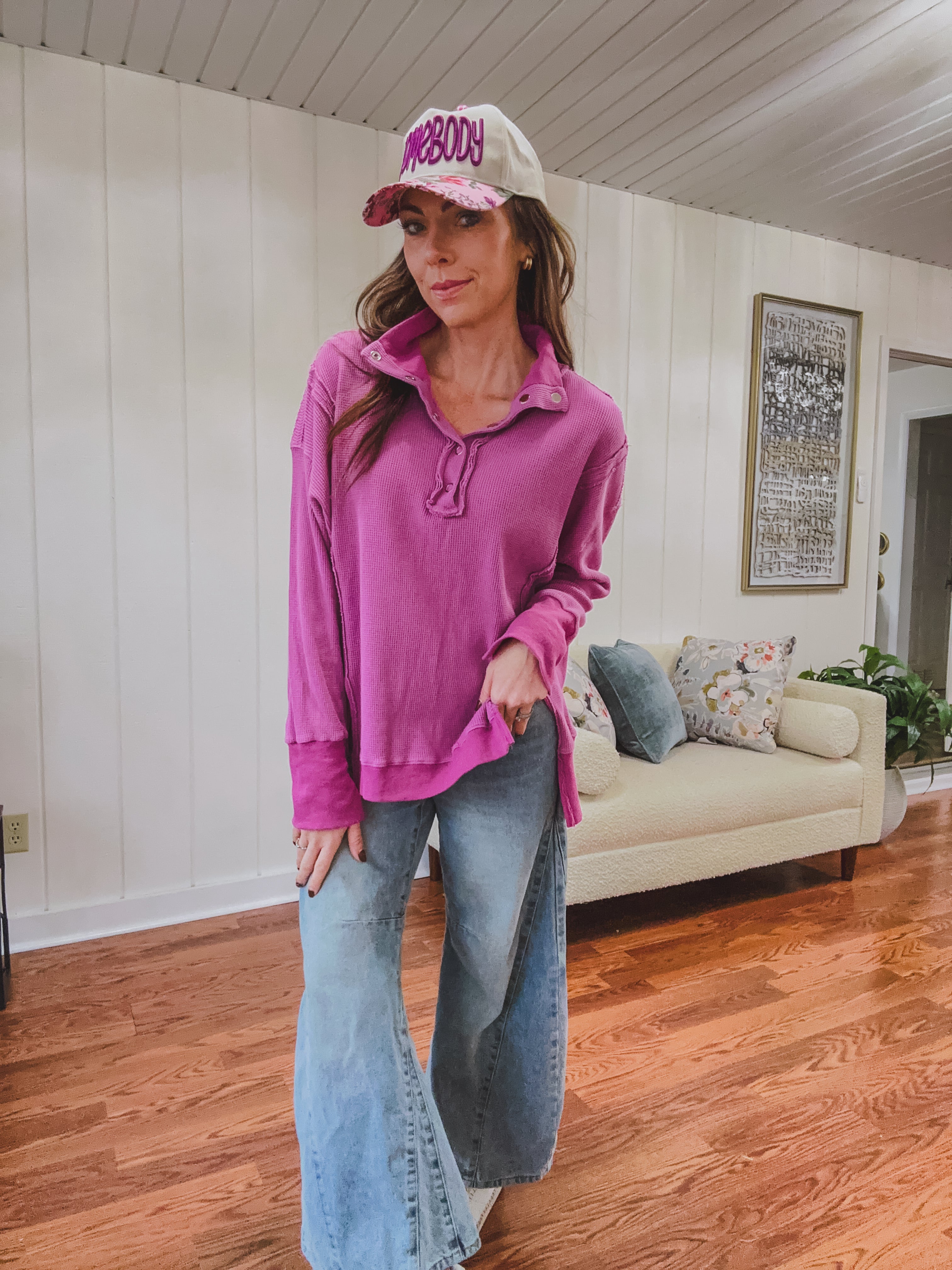 Woman wearing a pink long-sleeve top and jeans indoors.