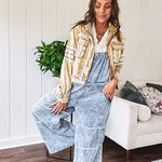 Vintage light wash denim and twill overalls with silver metal adjustable strap hardware, side zip, side and back pockets with ivory eyelet trim and cutouts throughout, wide leg design.