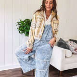 Vintage light wash denim and twill overalls with silver metal adjustable strap hardware, side zip, side and back pockets with ivory eyelet trim and cutouts throughout, wide leg design.