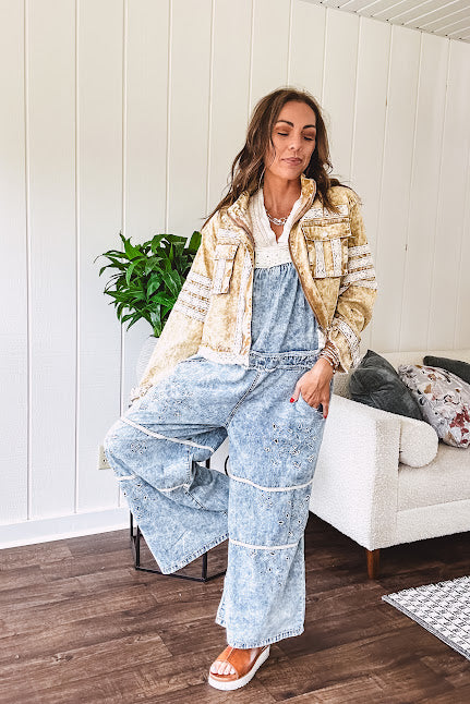 Vintage light wash denim and twill overalls with silver metal adjustable strap hardware, side zip, side and back pockets with ivory eyelet trim and cutouts throughout, wide leg design.
