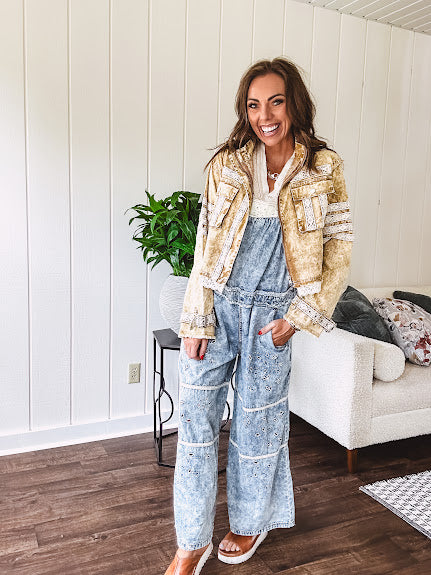 Vintage light wash denim and twill overalls with silver metal adjustable strap hardware, side zip, side and back pockets with ivory eyelet trim and cutouts throughout, wide leg design.