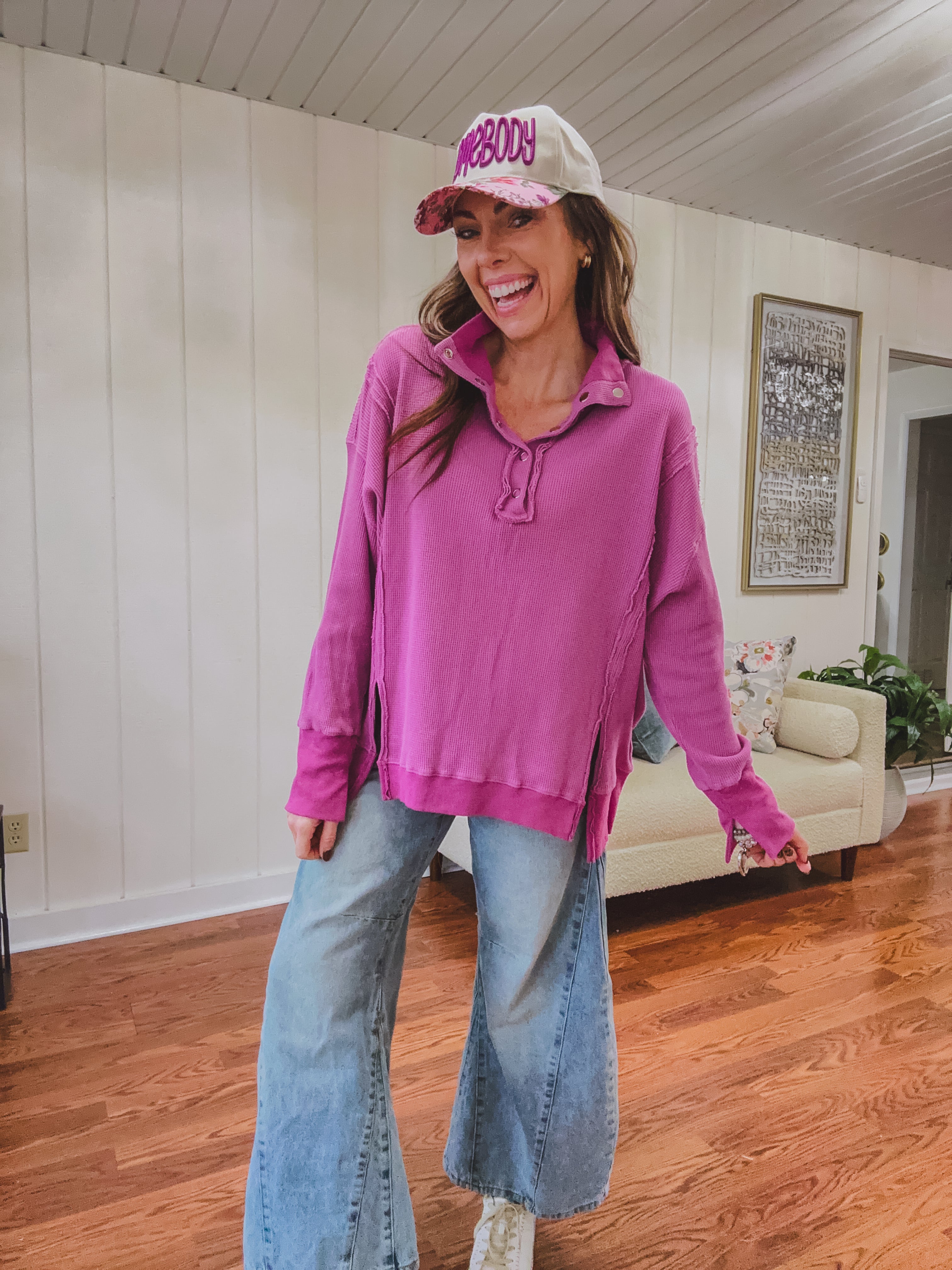 Woman wearing a pink hoodie and jeans indoors