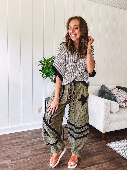Cotton lightweight moss green joggers with mauve dainty floral print and black knit striping and star patch detail throughout, button and zipper closure with rope grommet stye belt, side pockets and elastic cuffs.