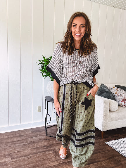 Cotton lightweight moss green joggers with mauve dainty floral print and black knit striping and star patch detail throughout, button and zipper closure with rope grommet stye belt, side pockets and elastic cuffs.