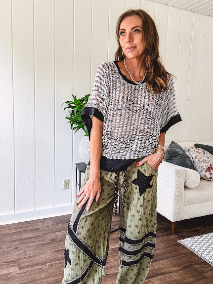 Cream and black striped open weave pullover with contrasting black trim at the short sleeve cuffs and round neck with a slouchy fit.