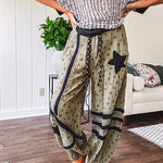 Cotton lightweight moss green joggers with mauve dainty floral print and black knit striping and star patch detail throughout, button and zipper closure with rope grommet stye belt, side pockets and elastic cuffs.