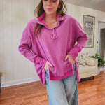 Woman wearing a pink sweatshirt and cap in a living room.