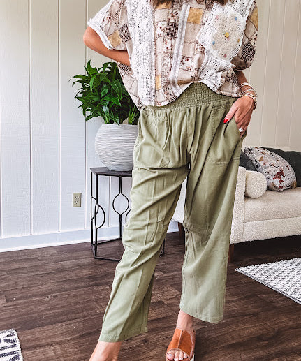 Lightweight olive smocked waist pants with side pockets and knee darts, cropped style.