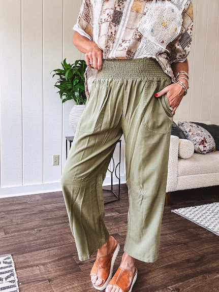 Lightweight olive smocked waist pants with side pockets and knee darts, cropped style.