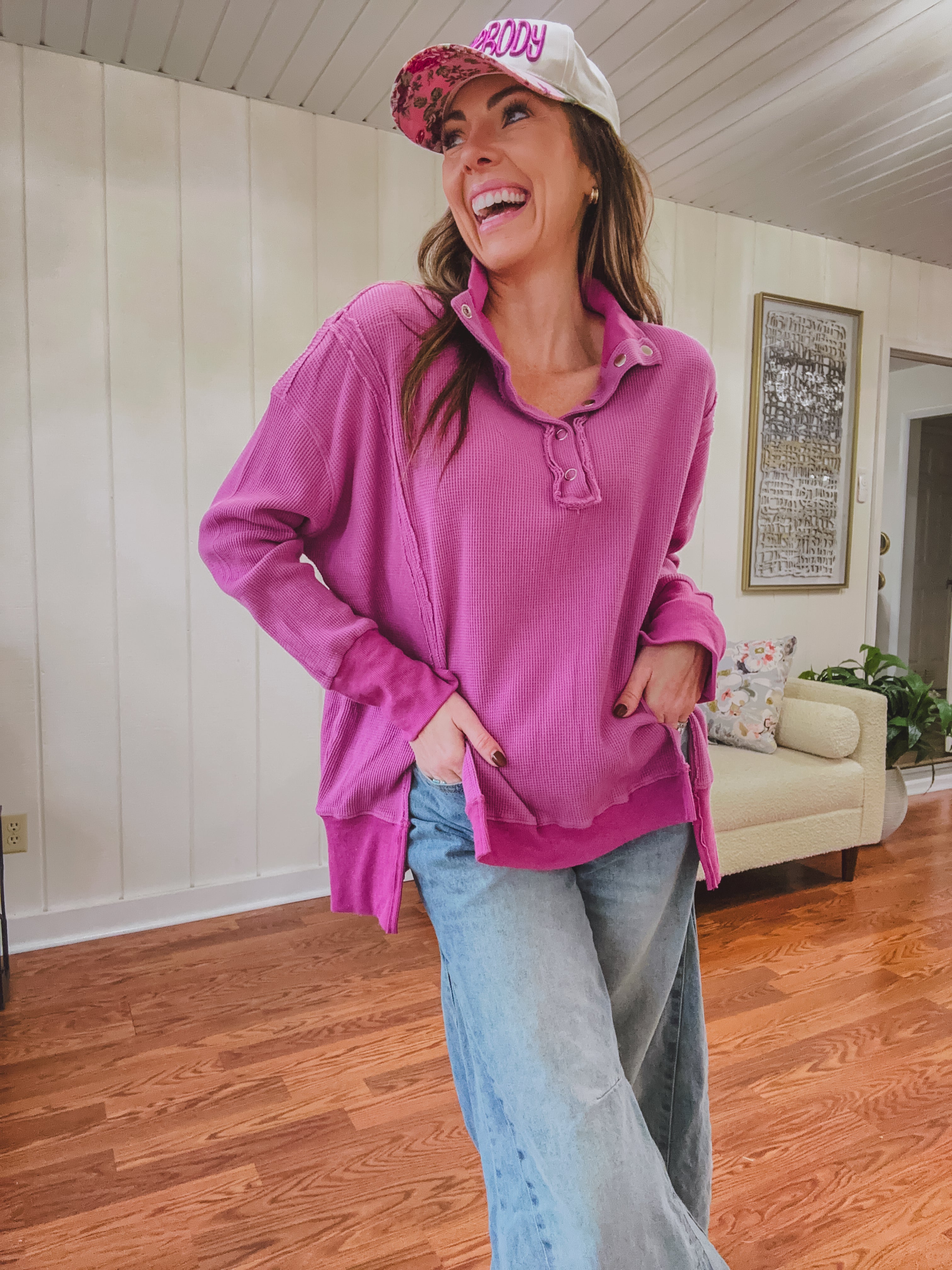 Woman wearing a pink sweatshirt and cap indoors