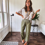 Lightweight olive smocked waist pants with side pockets and knee darts, cropped style.