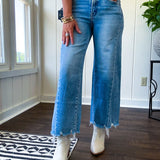 Cropped tattered hem wide leg medium wash denim jeans.