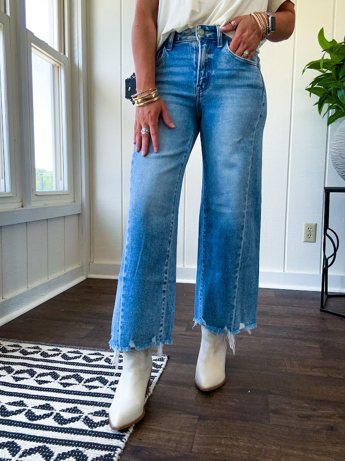 Cropped tattered hem wide leg medium wash denim jeans.