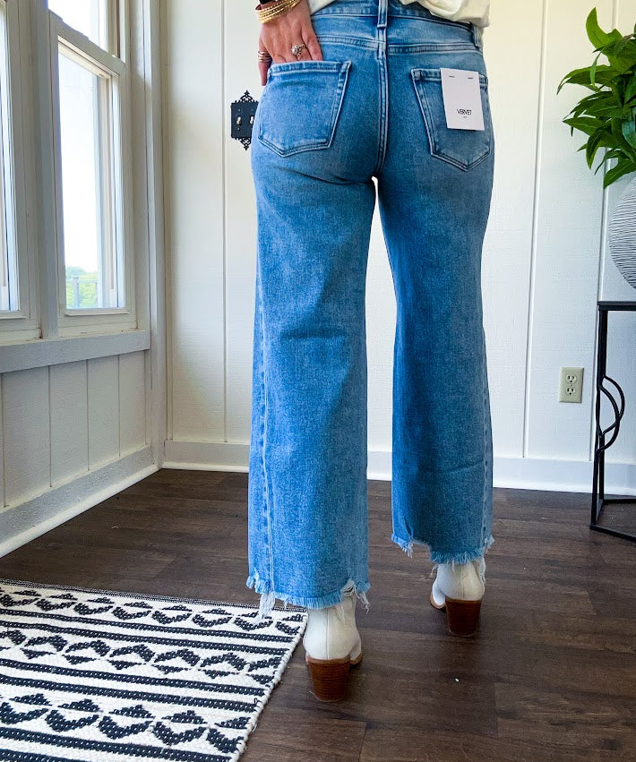 Cropped tattered hem wide leg medium wash denim jeans.