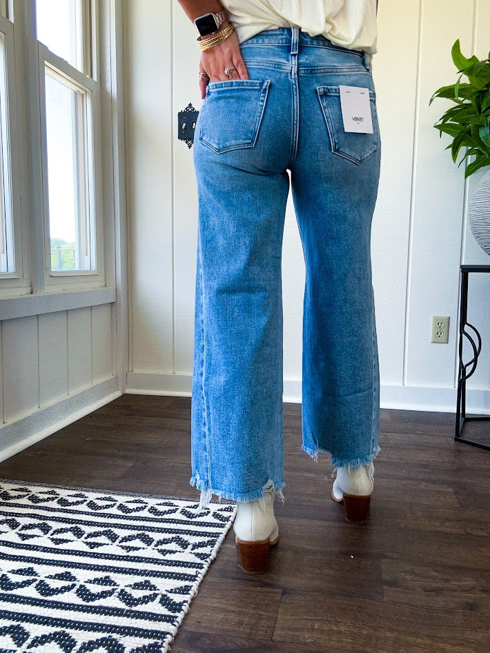 Cropped tattered hem wide leg medium wash denim jeans.