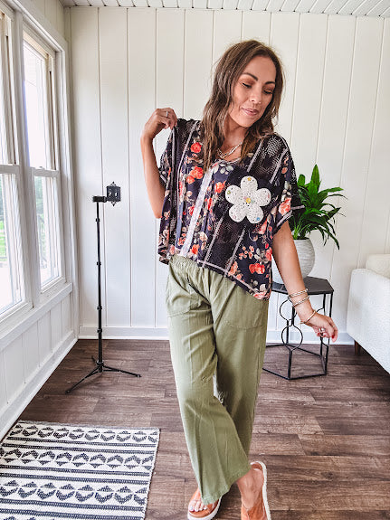 Lightweight black V neck tee with coral rose floral print throughout, raw seams and black ace inserts and ivory floral crochet patchwork on the front pocket.