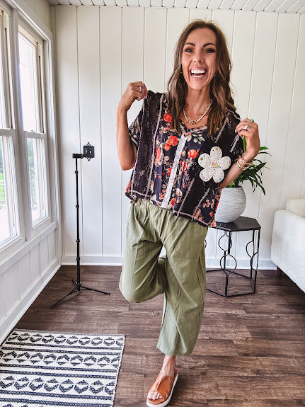 Lightweight black V neck tee with coral rose floral print throughout, raw seams and black ace inserts and ivory floral crochet patchwork on the front pocket.