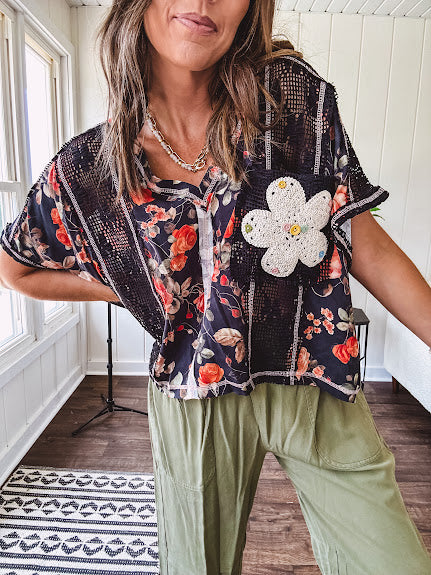 Lightweight black V neck tee with coral rose floral print throughout, raw seams and black ace inserts and ivory floral crochet patchwork on the front pocket.