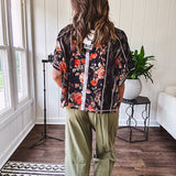 Lightweight black V neck tee with coral rose floral print throughout, raw seams and black ace inserts and ivory floral crochet patchwork on the front pocket.
