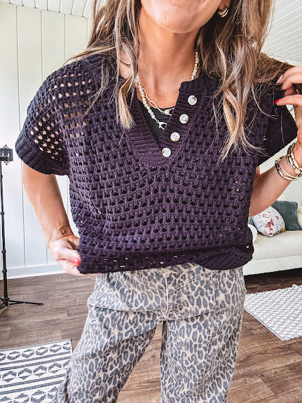 Black open knit sweater with short sleeves, four buttons down the V neck and ribbed hem and cuffs.